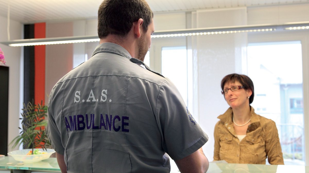 Ambulancier de dos parlant à une secrétaire